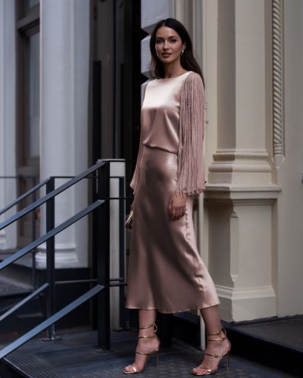 Lady standing in a white dress with silver jewelry and beige strappy heels